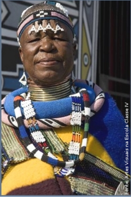 A Artista Sul-africana Esther Mahlangu de 75 anos, nascida em 1935, pertence à comunidade Ndebele de Gauteng, ao norte de Pretoria. Pioneira em colocar as cores e formas Ndebele em telas, até então realizadas somente nos murais das casas. Desenha à mão livre, sem medições ou esboços utilizando tintas brilhantes. A sua arte é fortemente marcada pelo estilo original de sua tribo, que emprega pinturas especiais nas paredes através de formas geométricas e multicoloridas. Em 1989, quando tinha 55 anos, foi a primeira mulher de sua tribo a cruzar o oceano, a transpôr os murais para telas e levar as convenções do seu trabalho a um público mais vasto. Isso aconteceu, porque viajou até Paris para criar os murais da exposição &ldquo;Magiciens de la Terre&rdquo;, e recebeu encomendas de trabalhos para museus e outros edifícios públicos como o Civic Theater de Johannesburgo, para a BMW, entre outras. Conquistou a Europa com sua pintura colorida e logo caiu nas graças de gente como Andy Warhol, Alexander Calder e Frank Stella.
<br/><br/>
Palavras-chave: artista esther mahlangu, pintura geométrica, ndebele, pintura em tela, pintura mural.